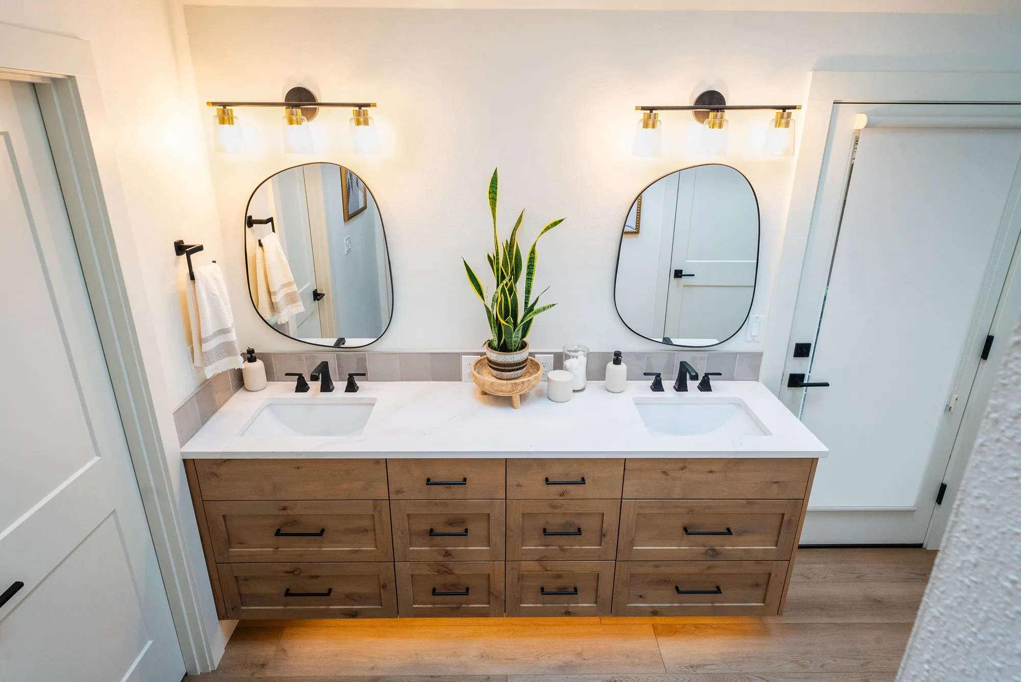 Dual vanity bathroom with brass light fixtures and LED underlight wired by Newman Electric in Vancouver WA