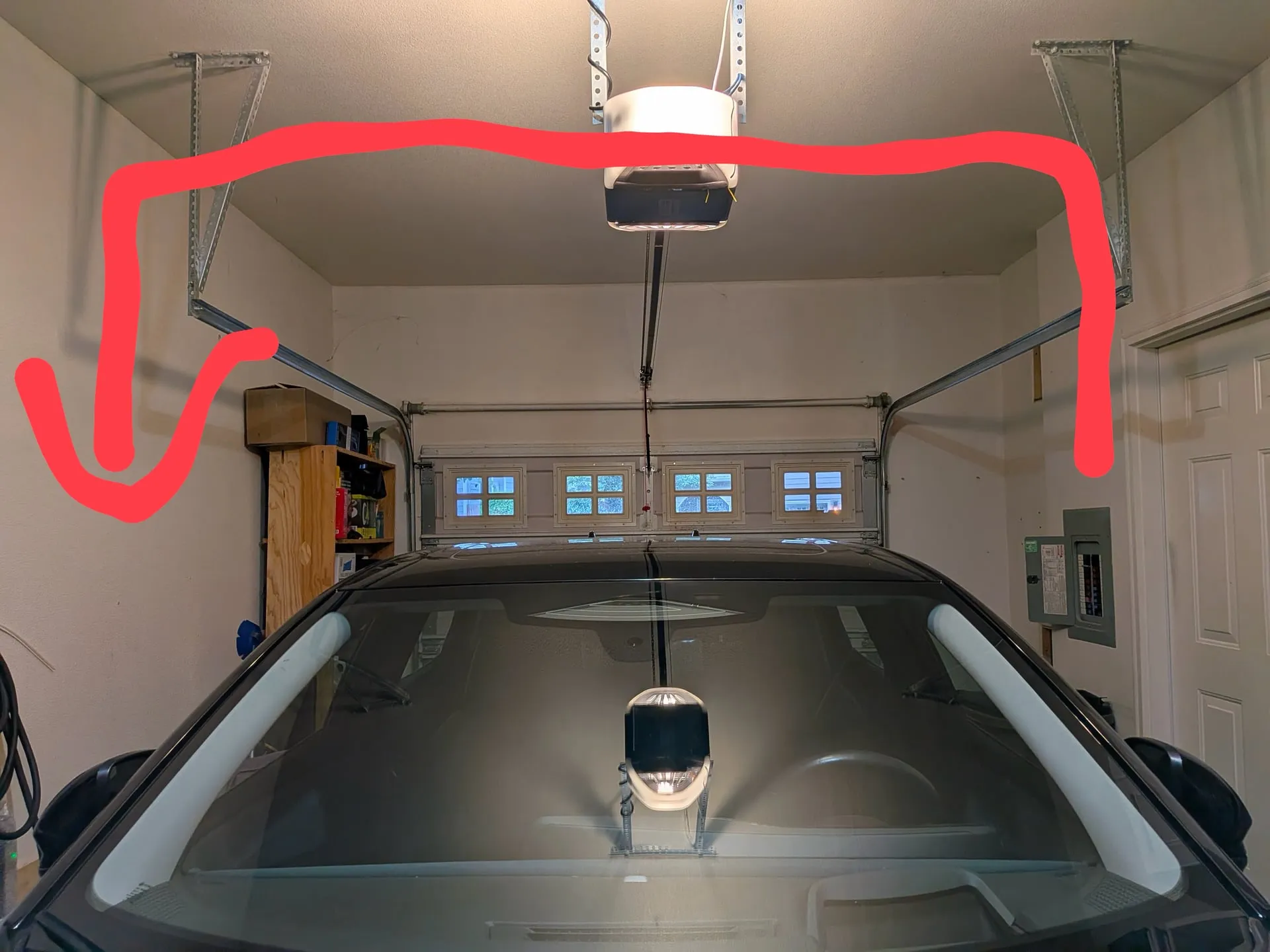 Photo of a Vancouver WA garage taken by the homeowner before the install, with a red line drawn across the ceiling past the garage door opener to show the planned charger route