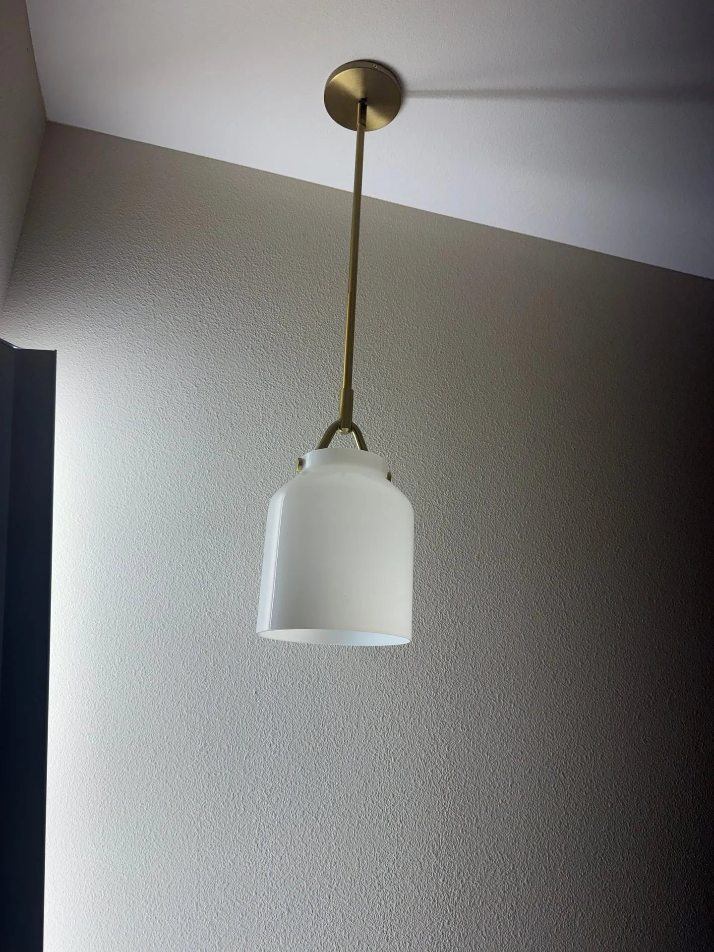 Brass stem pendant light with a white glass shade hanging from a ceiling canopy in a Ridgefield WA home