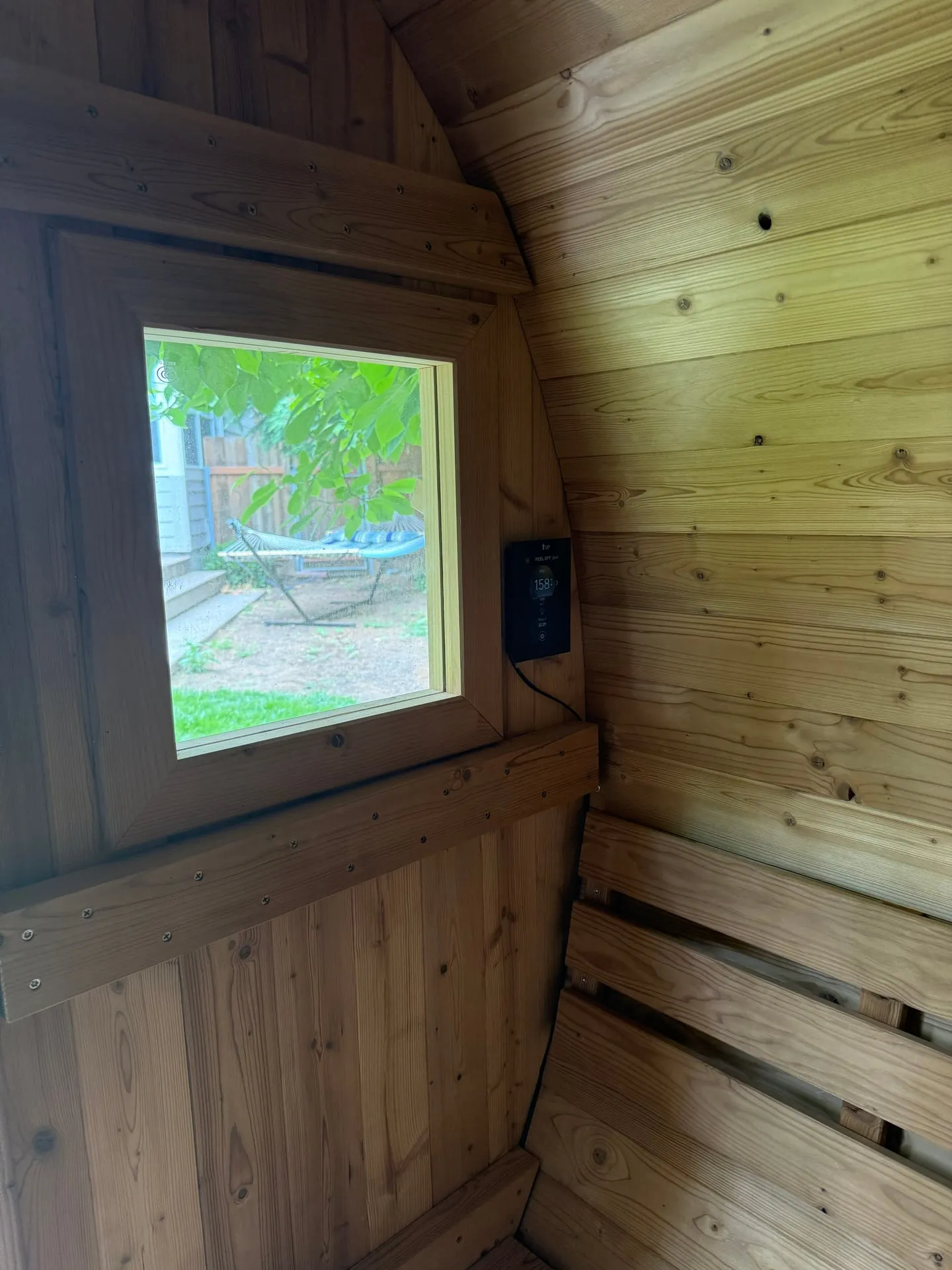 Digital sauna controller mounted on the cedar wall beside a window inside a Vancouver WA backyard sauna, reading a target temperature