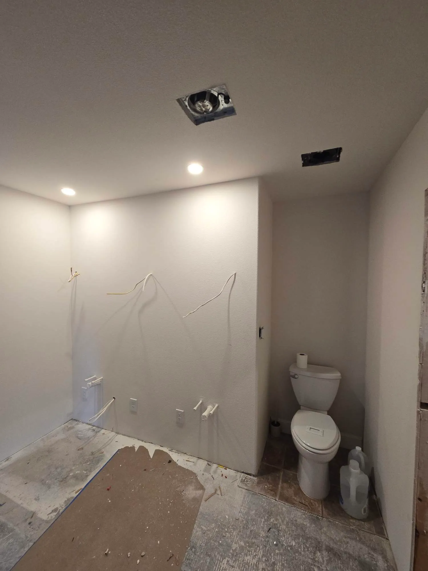 Bathroom and laundry area mid-trim in a Battle Ground WA remodel, with recessed cans, an exhaust fan rough opening in the ceiling, and device wiring left out at the wall boxes