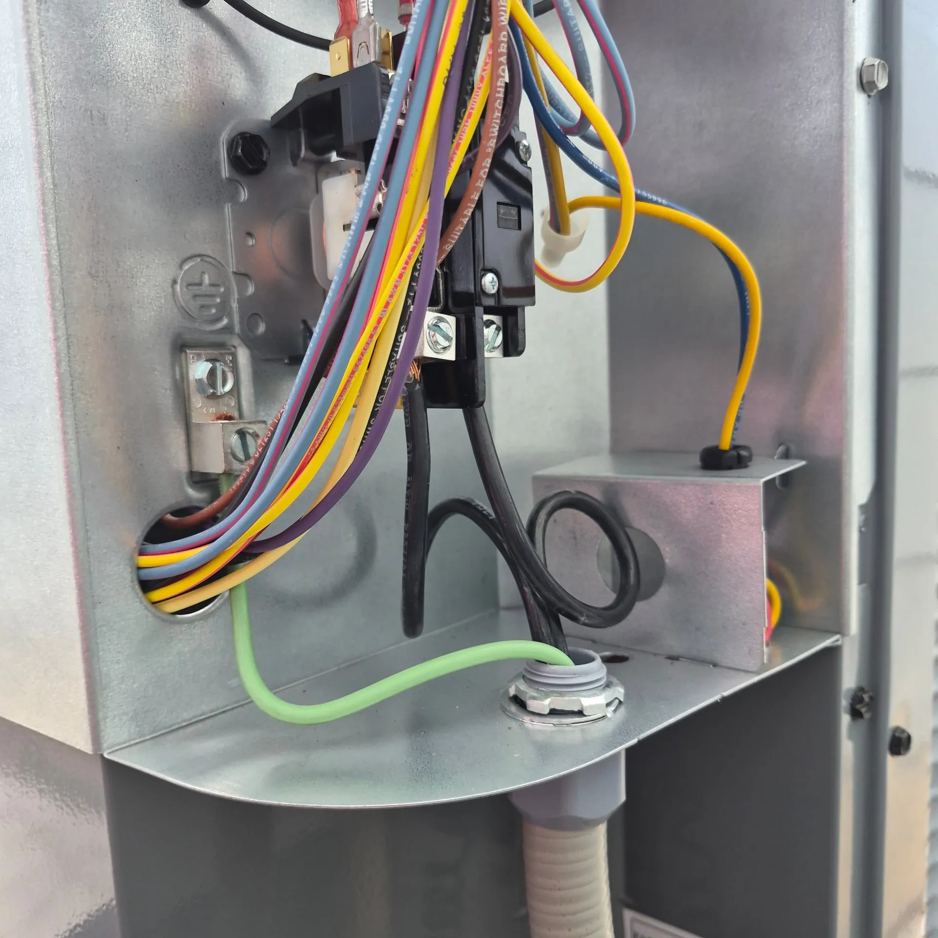 Inside the outdoor A/C disconnect on a Vancouver WA home, with line and load conductors landed on the pullout, a green ground wire bonded, and a sealtight connector entering the bottom