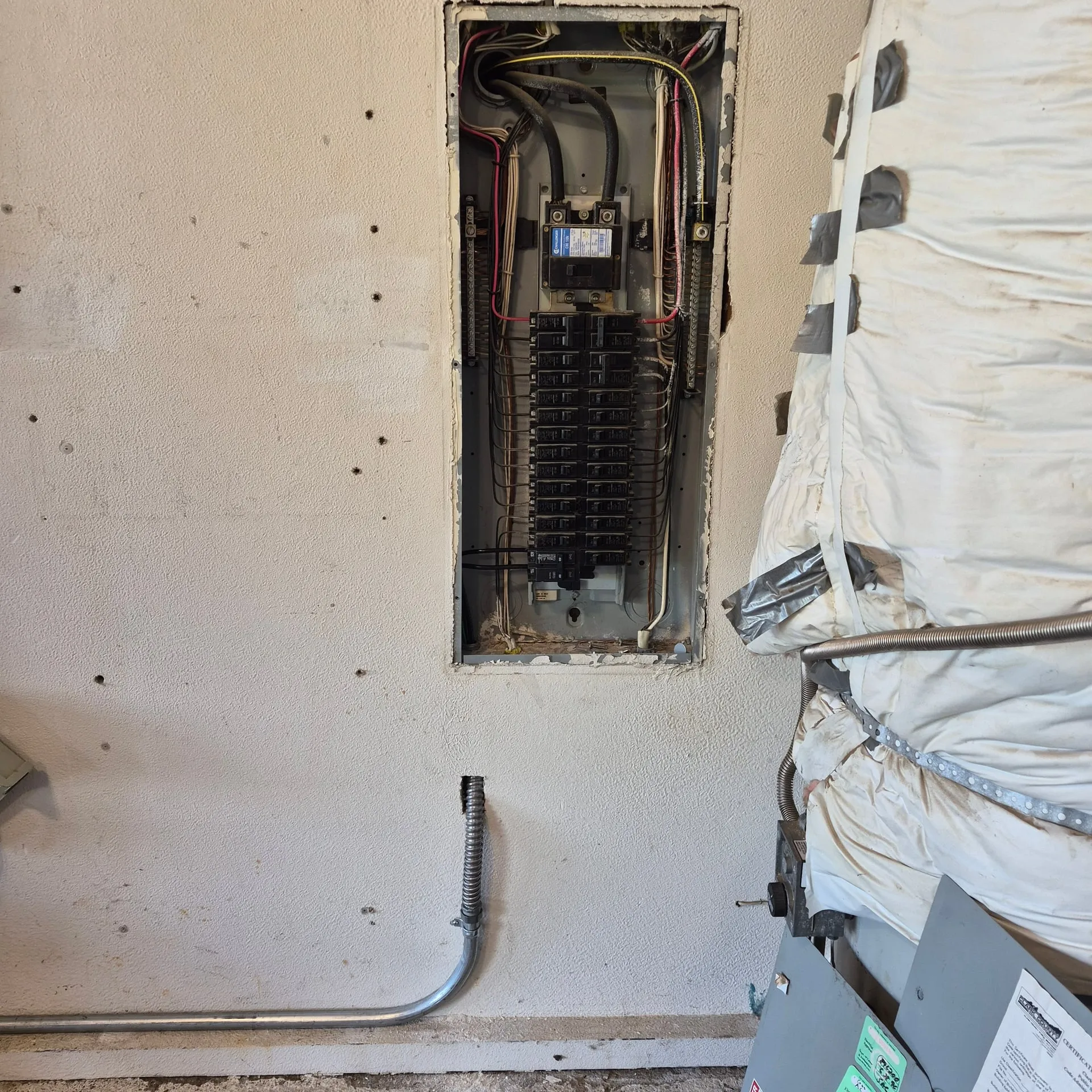 Open Eaton electrical panel recessed in a Vancouver WA garage wall with a new EMT conduit stub for the 60-amp EV charger circuit exiting the bottom and routing along the wall toward the charger