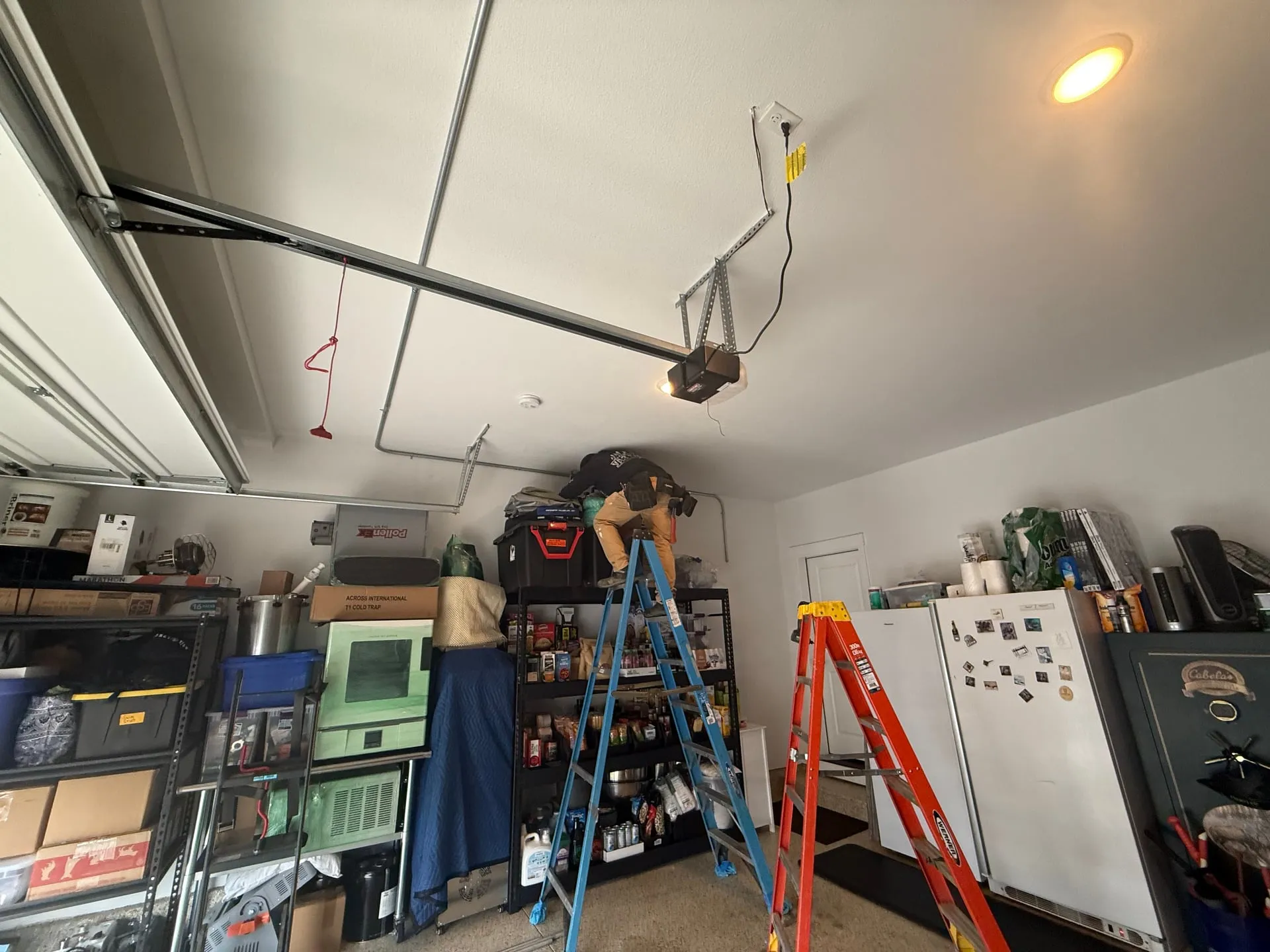 Electrician on a ladder running EMT conduit across the ceiling of a Ridgefield WA garage near the garage door opener to reach the EV charger location on the far wall