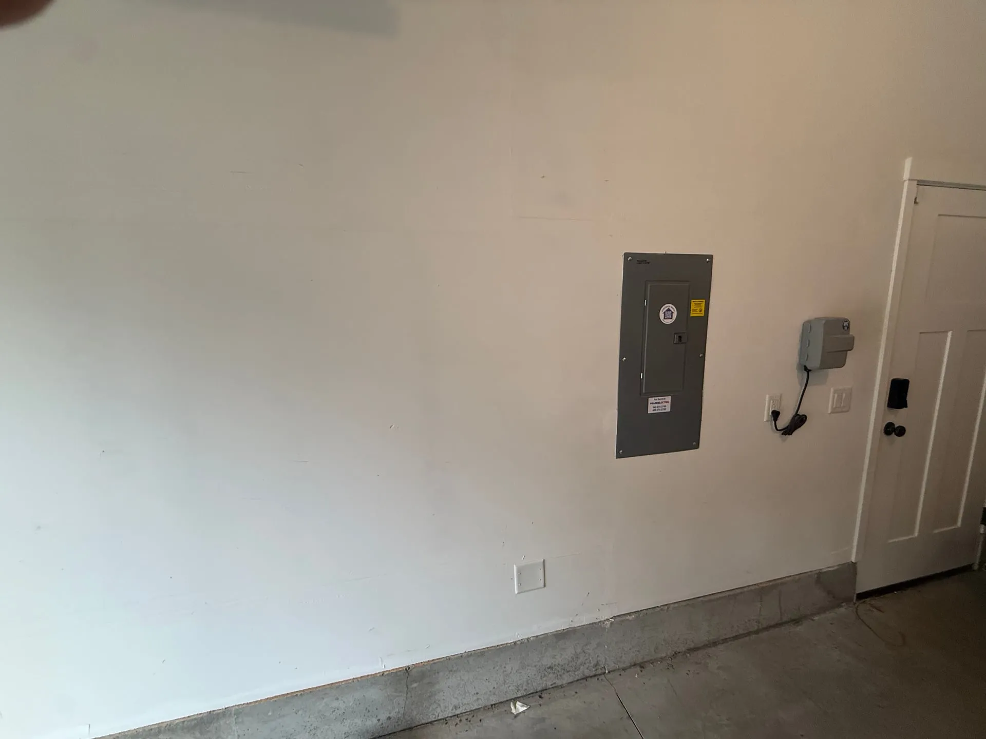 Garage wall in a 2022 Vancouver WA home with the Square D panel and a nearby outlet before the EV charger was mounted alongside it