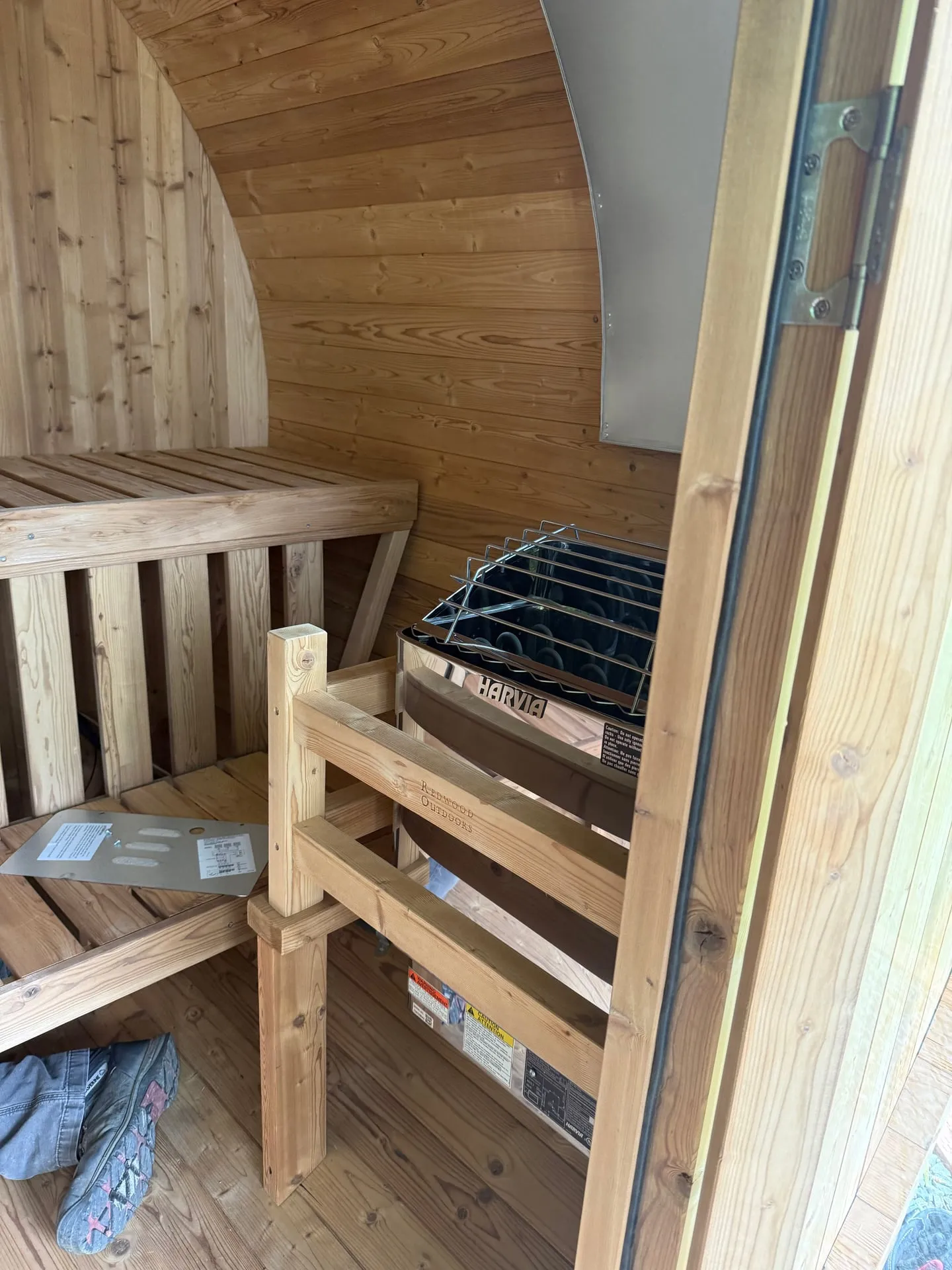 Interior of a cedar barrel sauna in a Vancouver WA backyard showing the Harvia electric sauna heater behind a guard rail next to the bench