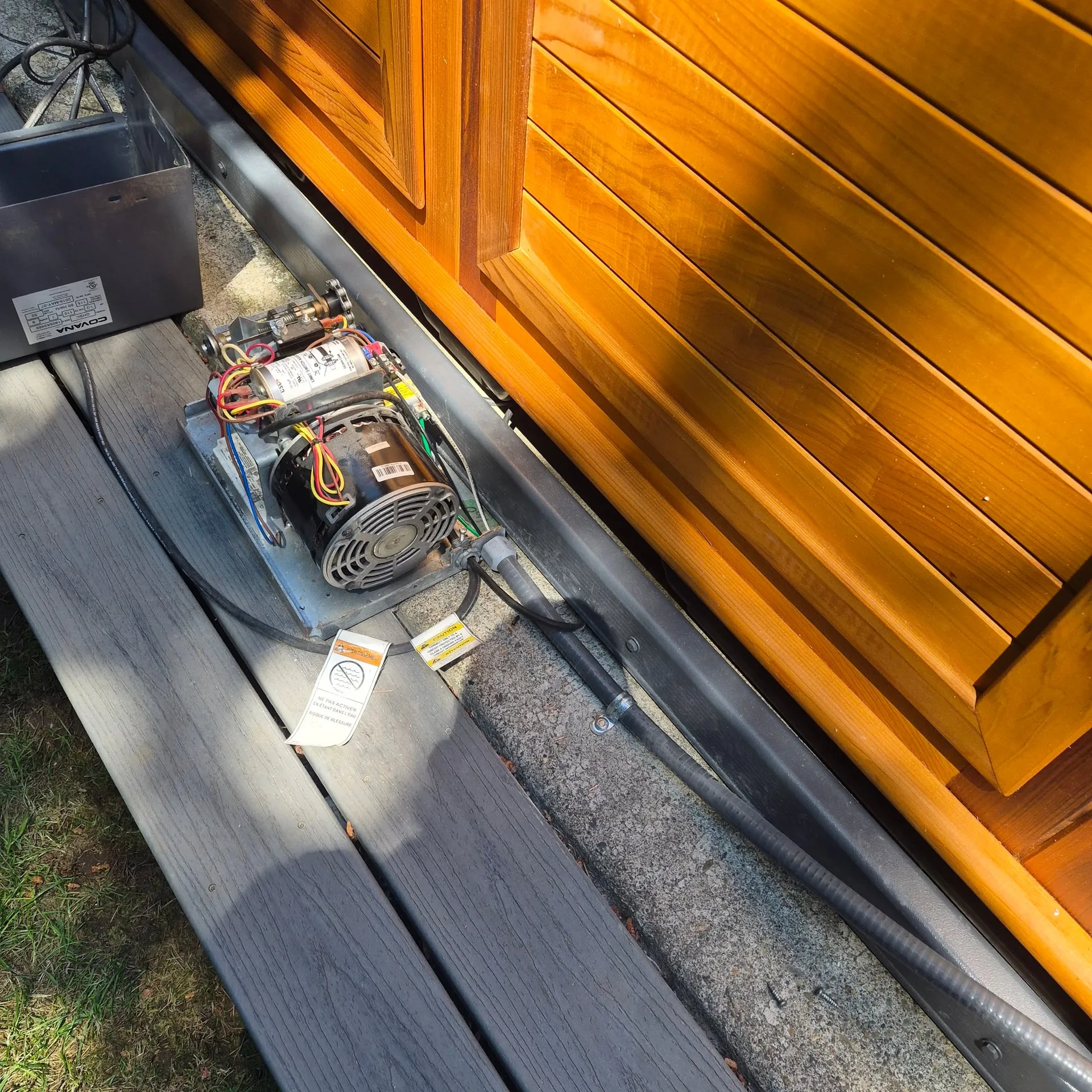 Hot tub pump motor and spa pack controller set out on the composite deck beside a cedar hot tub during the wiring at a Brush Prairie WA home
