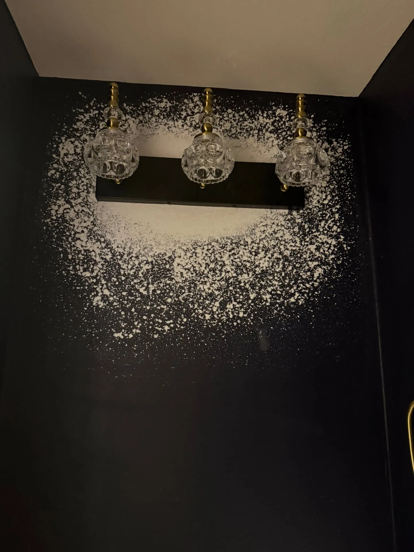 3-bulb crystal-and-brass vanity light mounted on a deep black textured wall in the remodeled guest bathroom of a Hazel Dell home in Vancouver WA