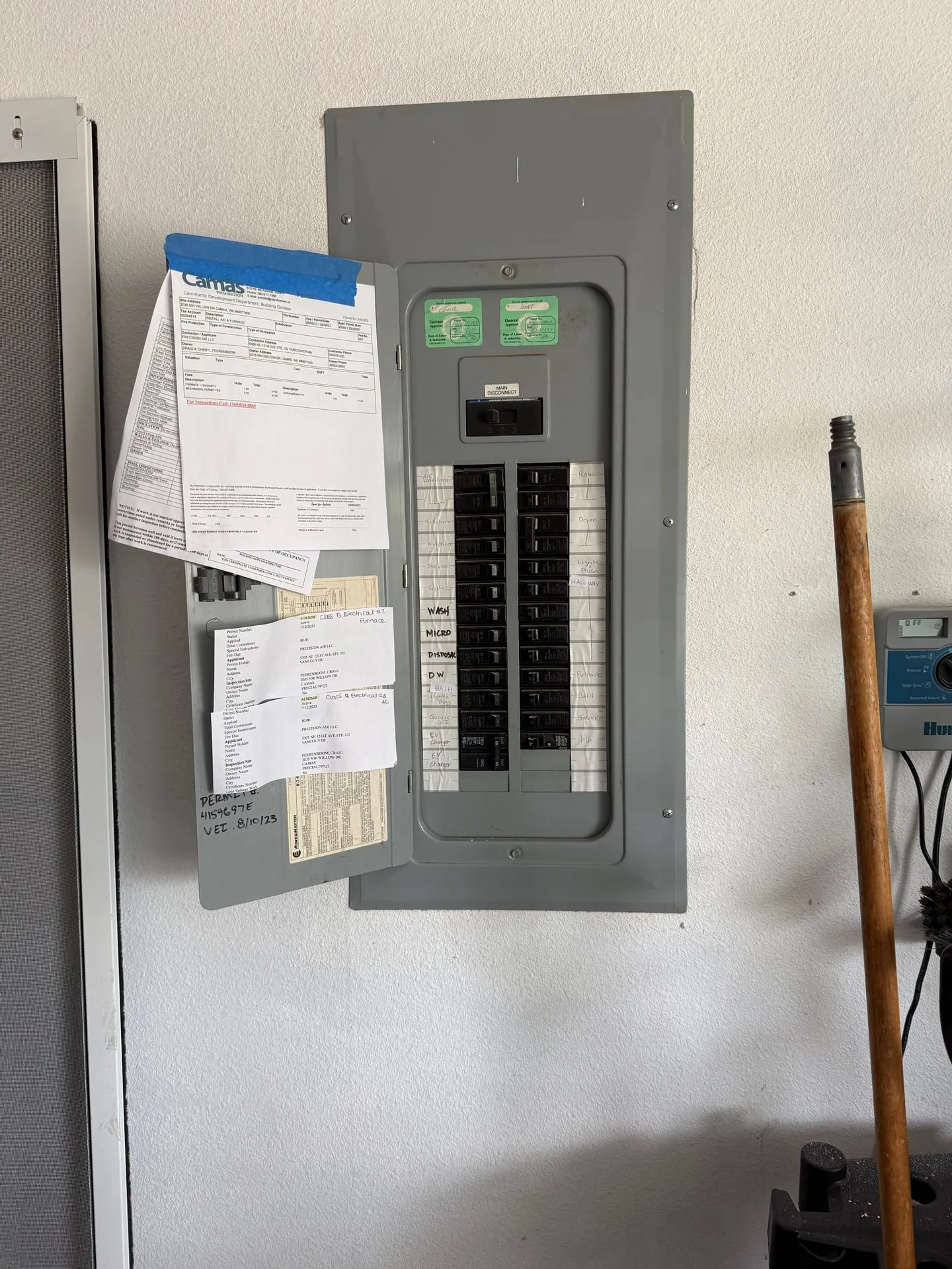 Eaton main panel in a Camas WA garage with a fully relabeled directory and two new EV charger breakers added at the bottom, with City of Camas and Washington L&I permit paperwork taped to the panel door