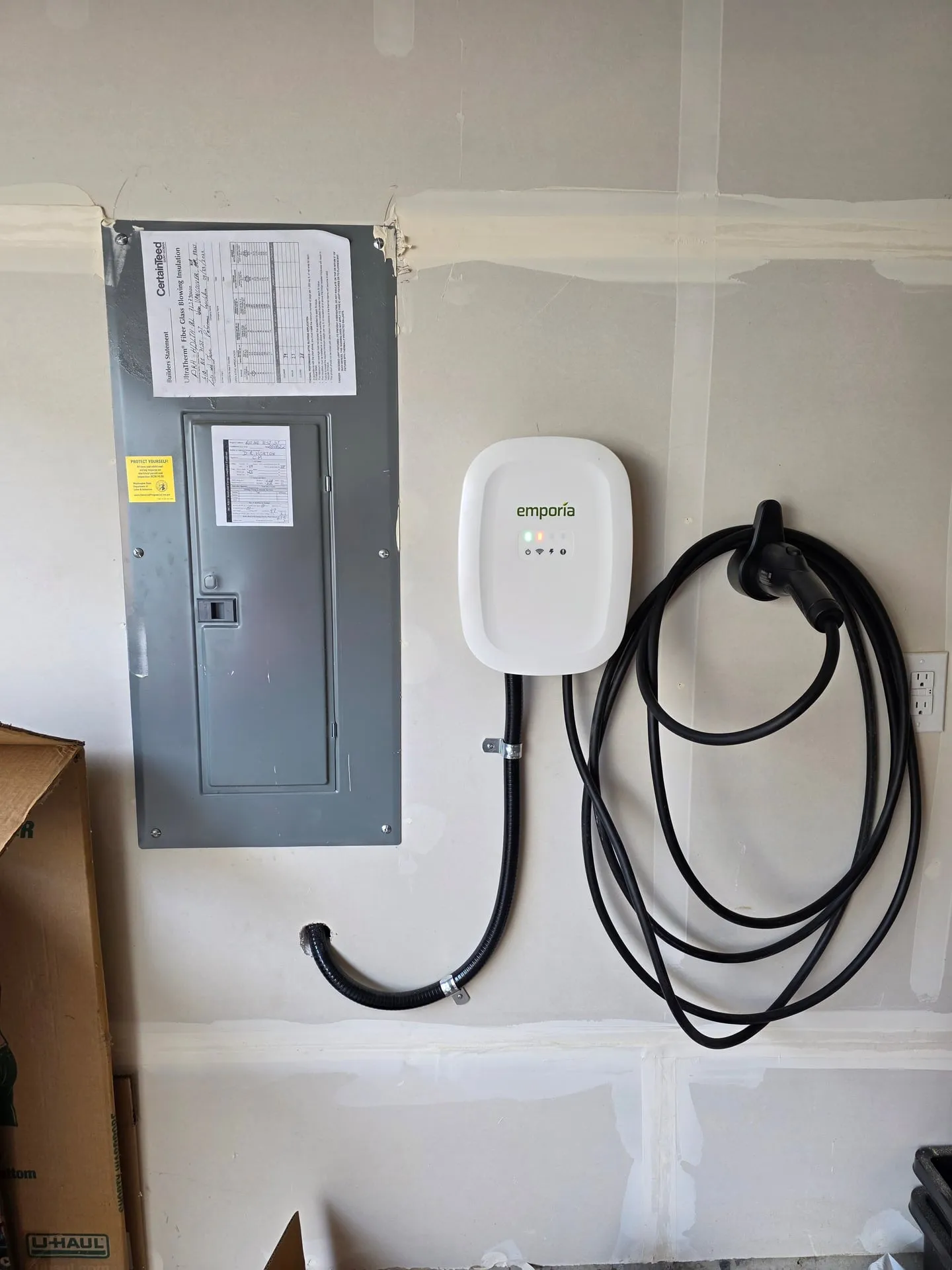 Emporia Level 2 EV charger mounted next to the main panel in a Hazel Dell garage, Vancouver WA, with a short flexible metal conduit run and the J1772 cord coiled ready to charge