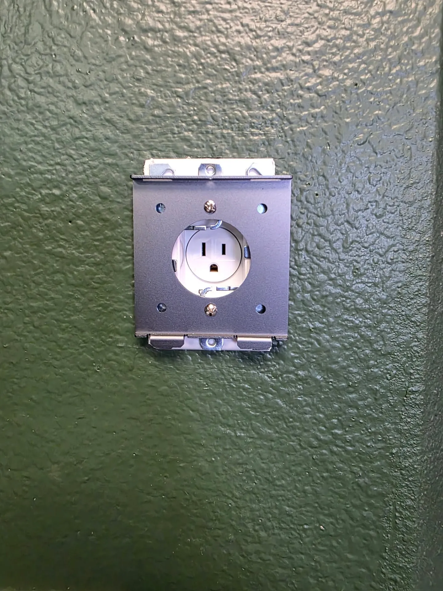 Recessed clock outlet with a metal plate set into a green textured wall in a Vancouver WA home, ready for a wall-mounted iPad