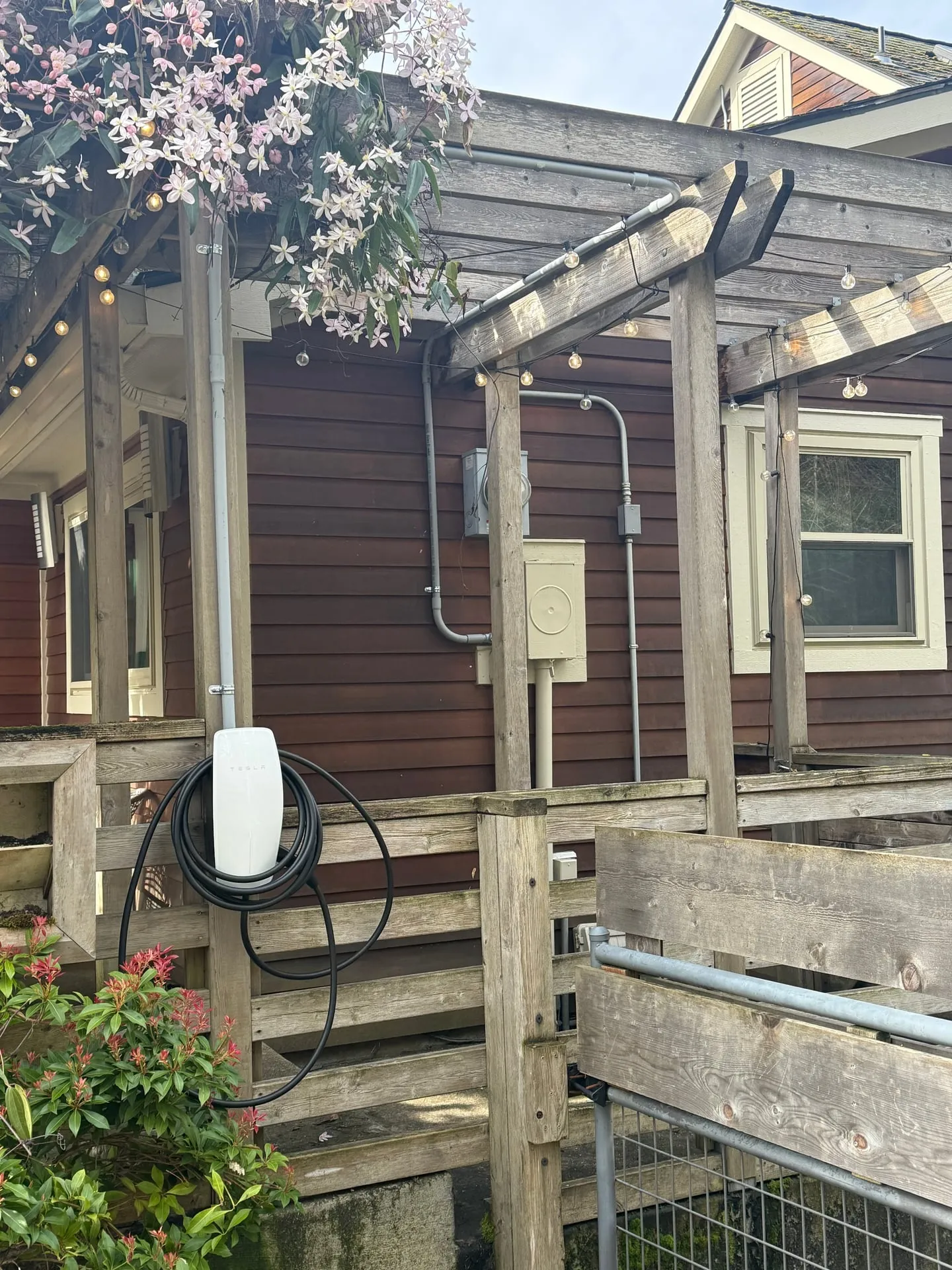 Tesla Wall Connector mounted outdoors on a pergola post at a Felida home in Vancouver, WA, installed by Newman Electric with conduit routed along the existing pergola structure