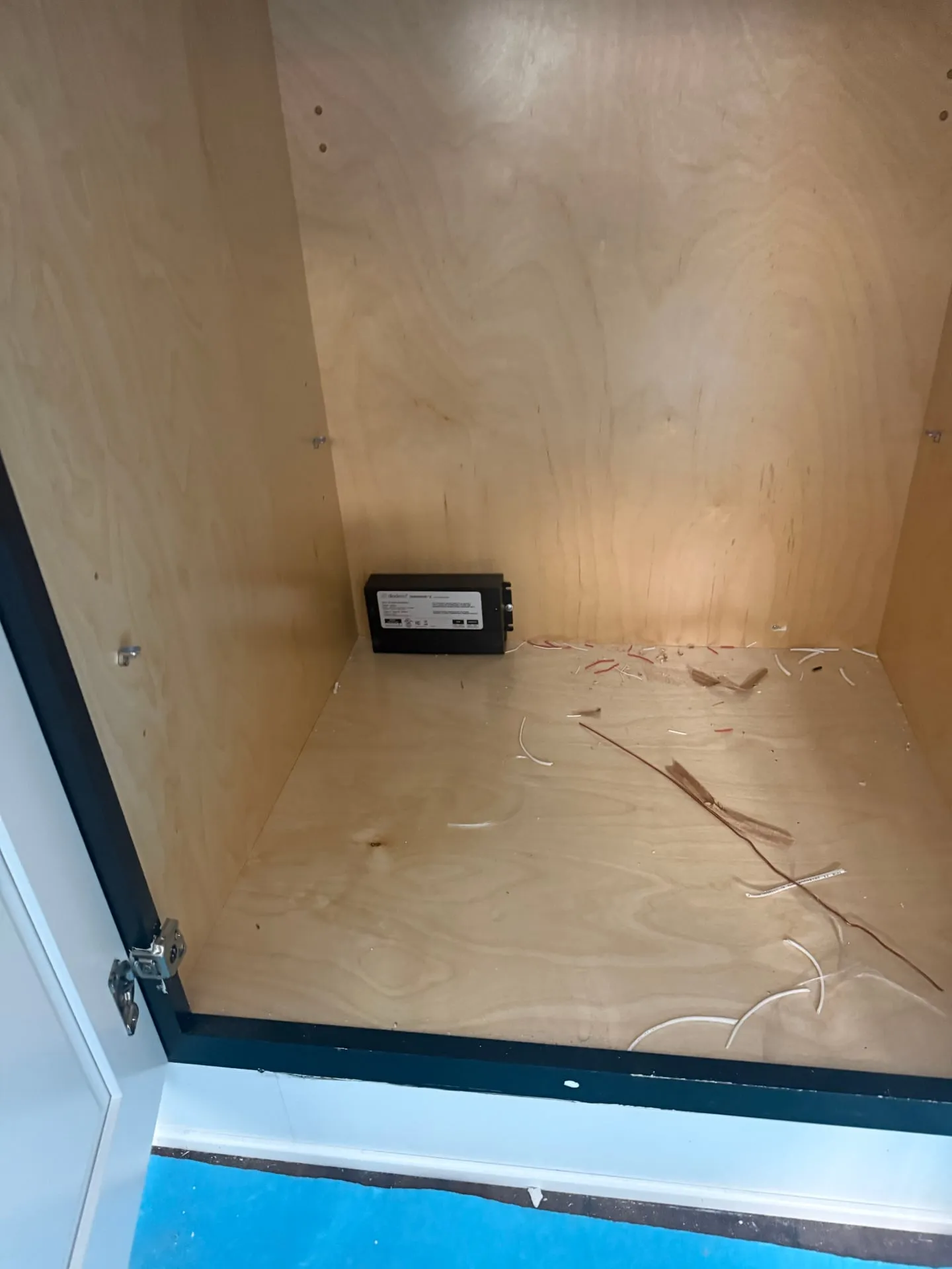Black LED driver mounted on the floor of an empty birch base cabinet in a Washougal WA kitchen, with low-voltage leads coming through the cabinet back