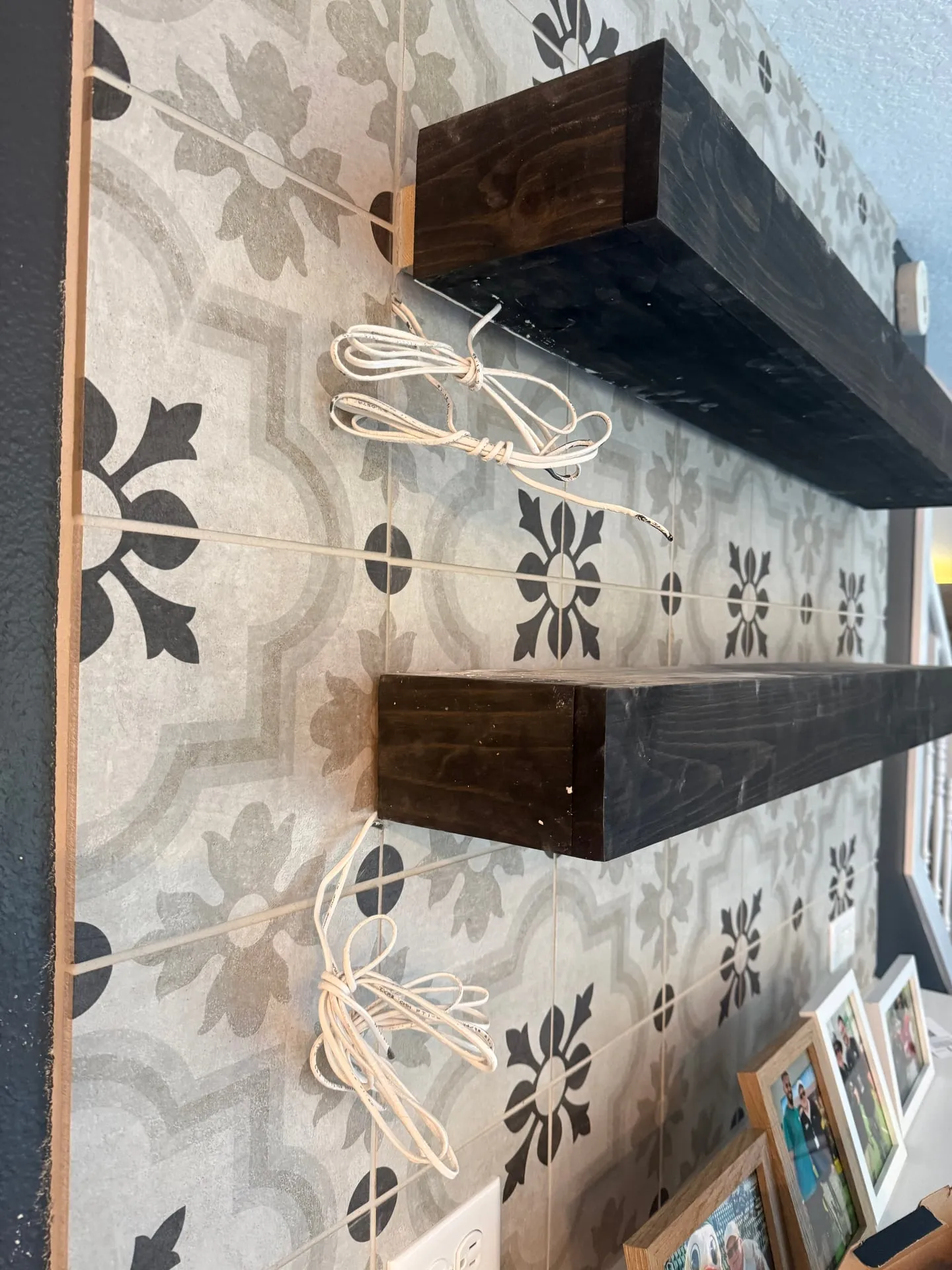 Dark wood floating shelves on patterned black and white cement-look tile with coiled lighting leads below each shelf in a Washougal WA kitchen remodel