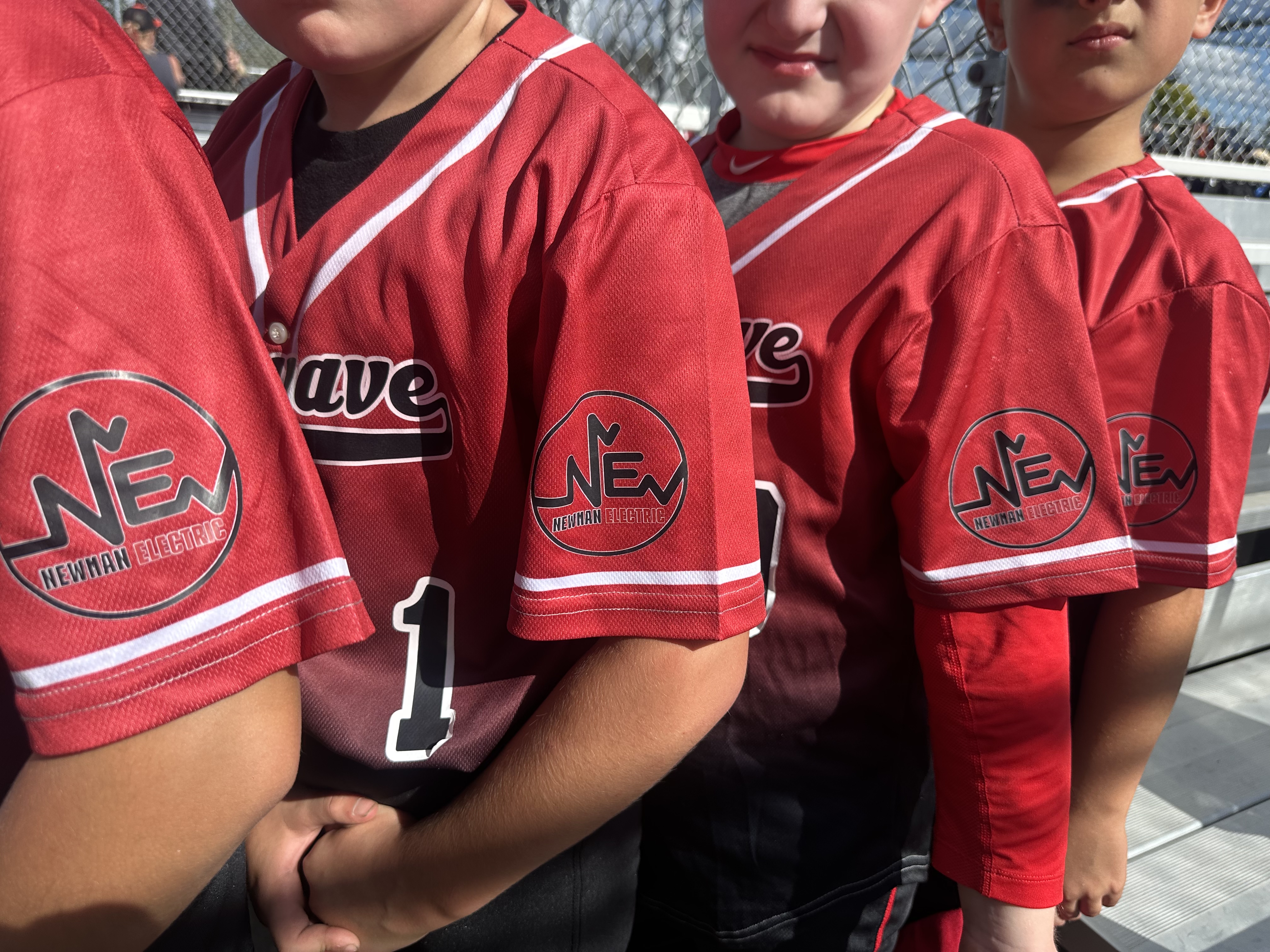 Kids wearing Newman Electric sponsored baseball jerseys at a local youth sports game